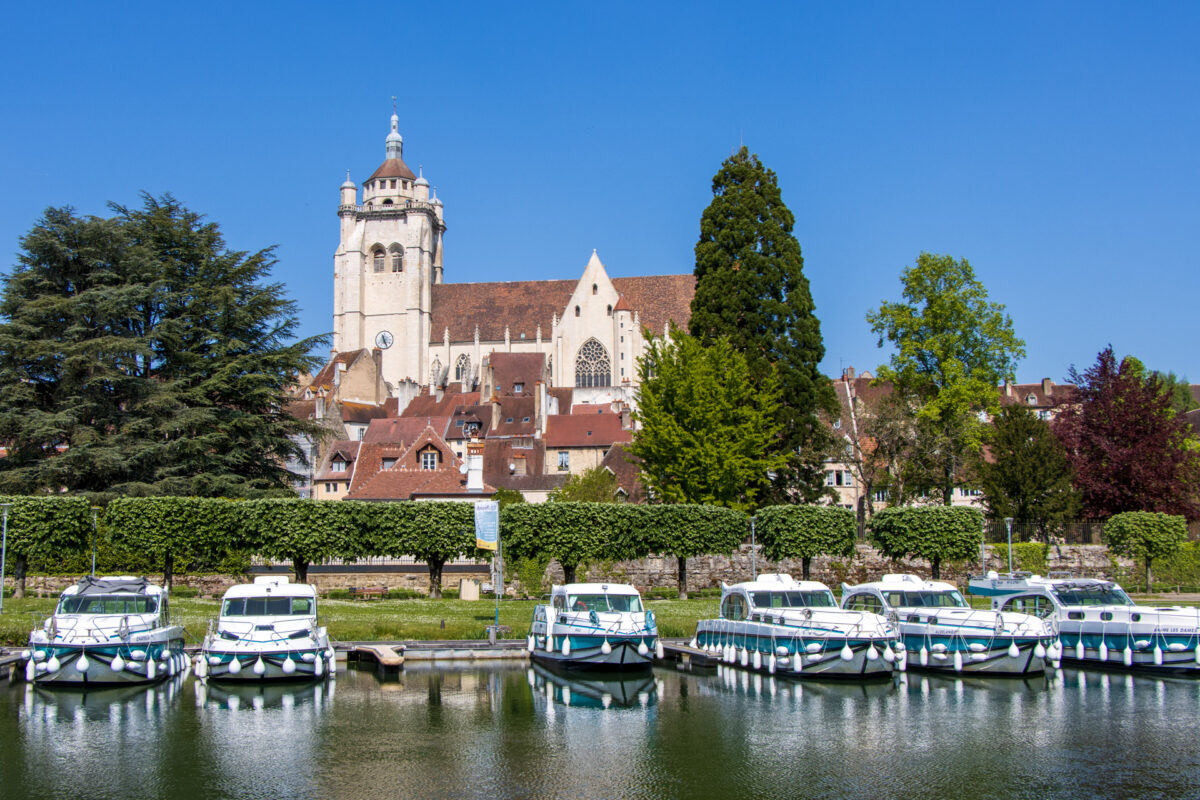 Am Ufer des Doubs in Dole. Im Vordergrund die Mietboote, im Hintergrund die Stiftskirche Notre-Dame.